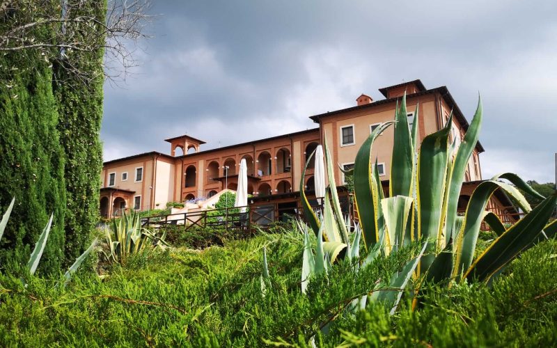 Edificio elegante con giardino verdeggiante sotto un cielo nuvoloso.